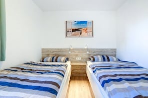 A room with two beds, a wooden headboard, and a framed picture on the wall. - Holiday apartment with 2 bedrooms (St. Peter-Ording)