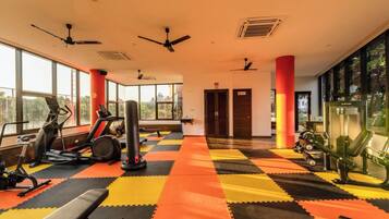 Une salle de sport équipée de matériel d’exercice, dotée de grandes fenêtres et d’un ventilateur de plafond.