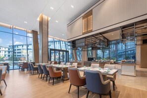 A modern dining area with high ceilings, large windows, and a view of the cityscape. - Pullman Taizhou Xianju (Taizhou)