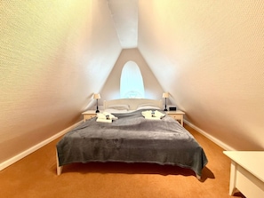 Ein Schlafzimmer mit einem Bett, Nachttischen und einem Fenster.