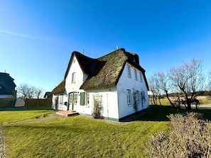A white house with a thatched roof, a front door, and a small front yard. - Deichhof Holiday Apartment 8 (Dunsum)
