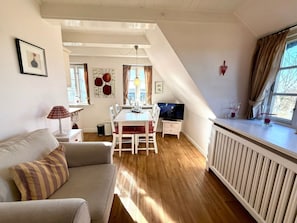 Ein modernes Wohnzimmer mit einer Couch, einem Esstisch und einem Fernseher.