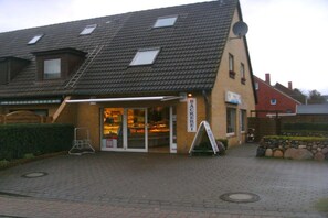 A building with a sloped roof, a glass storefront, and a sign that reads 'BAARACKEREI'. - Holiday apartment with 1 bedroom (Westerland - Sylt)