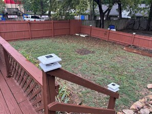 Ein umzäunter Garten mit einer Holzterrasse und einem kleinen Teich.