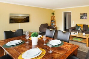 A dining area with a wooden table set for four, surrounded by chairs. - Holiday apartment in Sylt with swimming pool (Sylt)