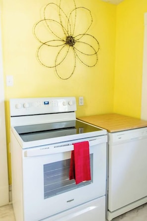 A kitchen with a white stove, a white oven, and a white dishwasher. - Cheerful & Homey ~ 7 Mins to Downtown ~ Queen Beds (Topeka)