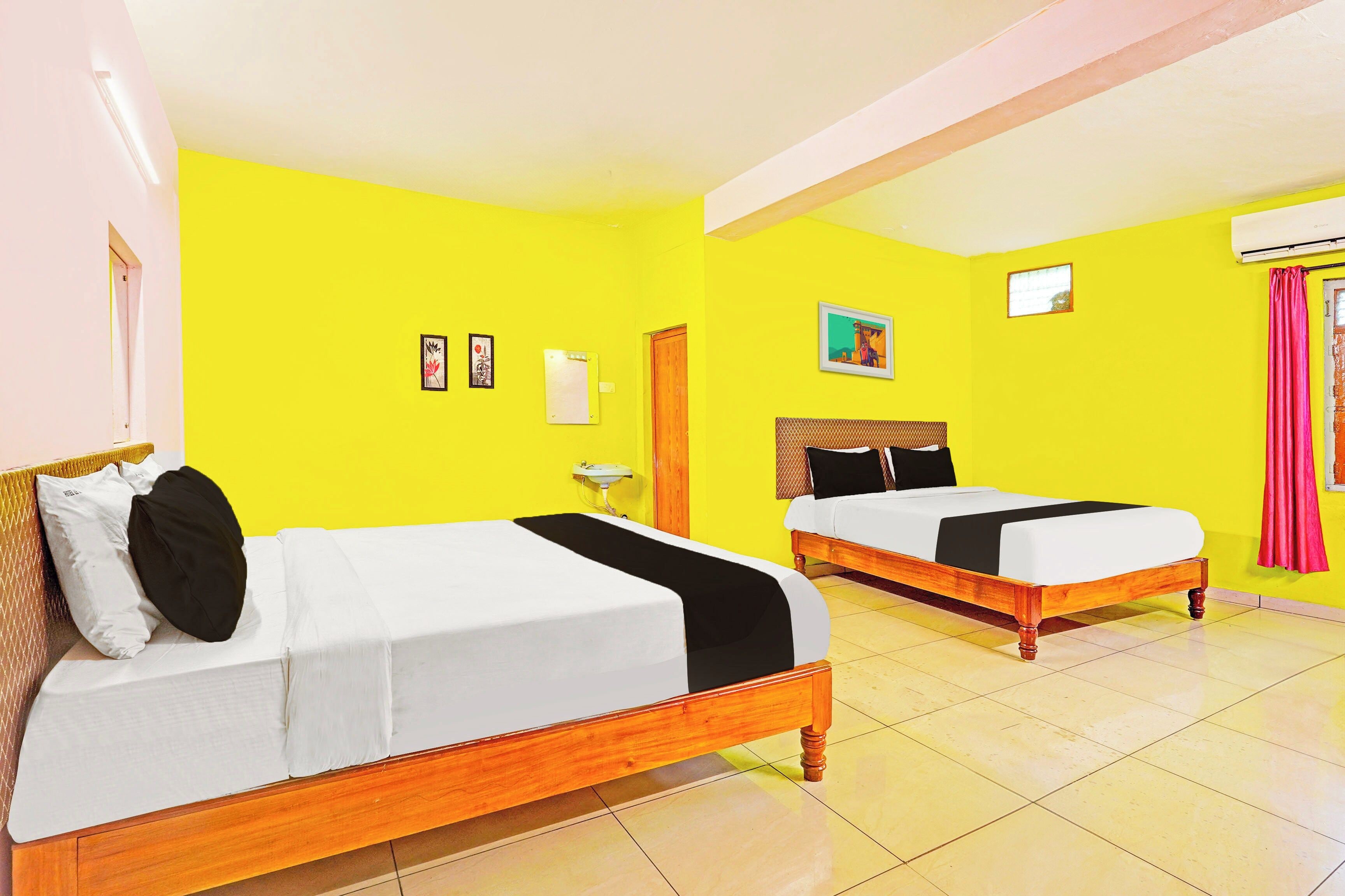 A hotel room with two beds, a sink, and a window with curtains.