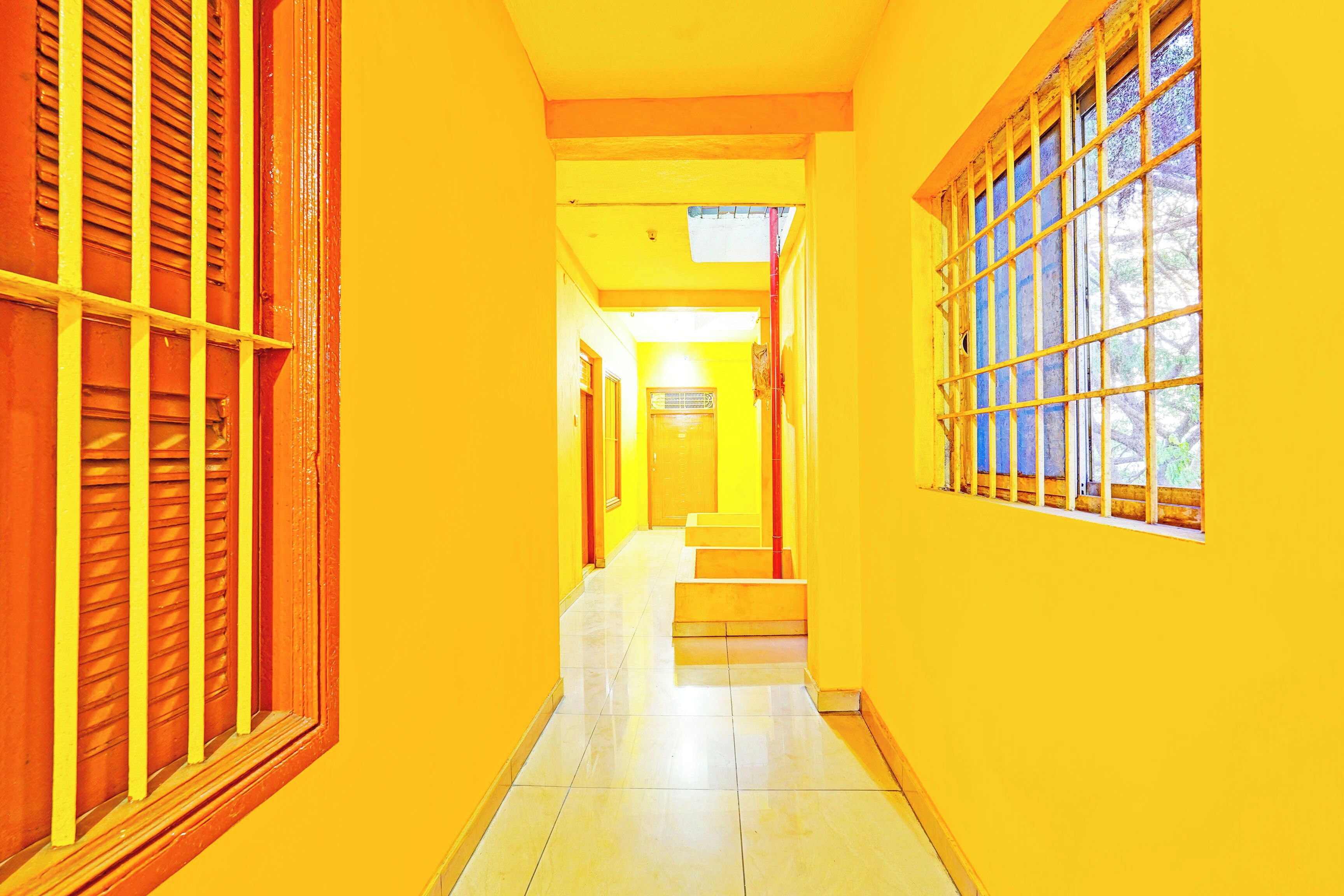 A corridor with a tiled floor and yellow walls.
