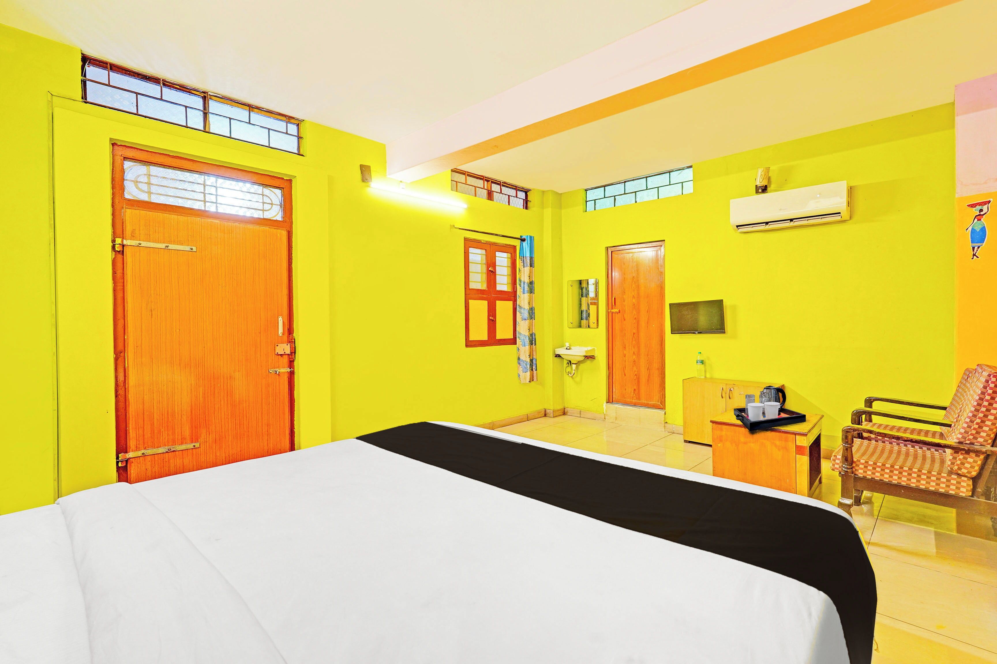 A room with a bed, a desk, a chair, and an air conditioning unit.