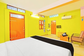 Quarto com cama, escrivaninha, cadeira e aparelho de ar condicionado.