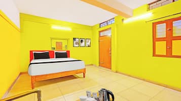Una habitación con cama, una mesa con tetera, tazas y una bandeja, además de una puerta con ventana.