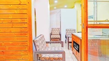 A hotel interior with wooden paneling, a reception desk, and patterned chairs.