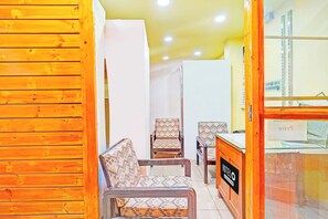 Interior de hotel com painéis de madeira, balcão de recepção e cadeiras estampadas.