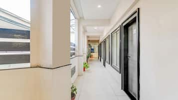 Un pasillo con vista a una vía de tren, plantas en macetas y una puerta marcada con el número 204.