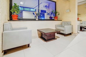Un moderno vestíbulo de hotel con una zona de estar, un ventanal con plantas y una recepción visible.