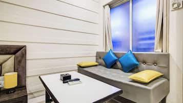 A room with a sofa, a table, a window with curtains, and a lamp.