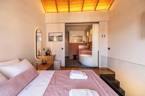 A modern hotel room with a large bed, a bathroom with a shower, and a view of the city through the window. - Mimosa Veneziano - Sauna - Old Town Chania (Chania)