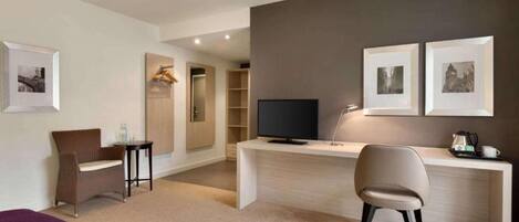 A modern hotel room with a desk, a chair, a television, and a bed.