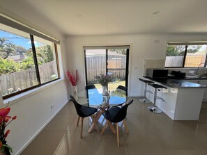 A modern kitchen with a dining area, large windows, and a view of the backyard. - Beautiful and spacious house in Doveton (Doveton)