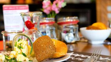 Un desayuno con huevos revueltos, un muffin y un bol de fruta.