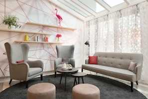 Una sala de estar moderna con un sofá, dos sillones, una mesa de centro y una lámpara de pie.