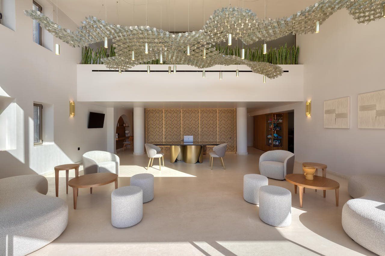 Un interior moderno con una mesa central, asientos y un techo decorativo.