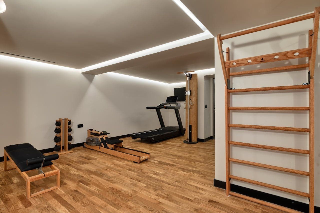 Un gimnasio con cinta de correr, equipo de ejercicio y un estante de madera.
