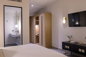 Quarto de hotel com cama, toucador com espelho, televisão na parede e guarda-roupa com espelho.
