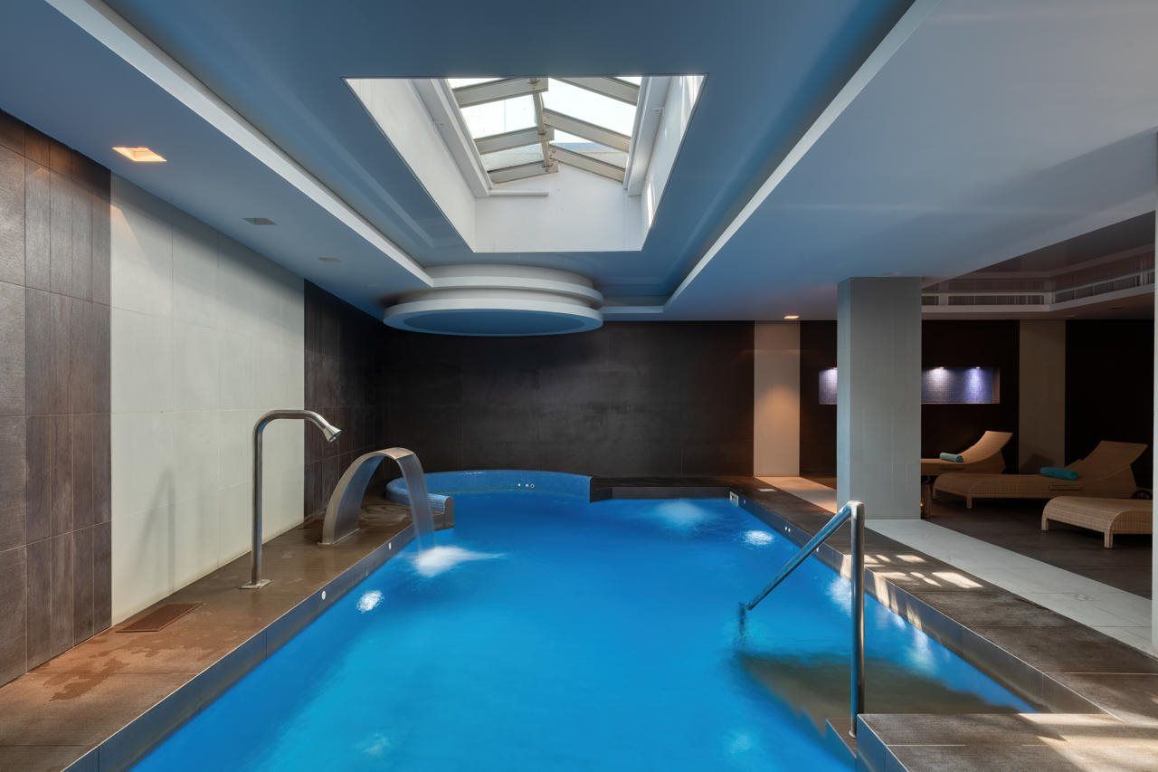 Una piscina con tragaluces, una zona de estar con sofás y un diseño interior moderno.