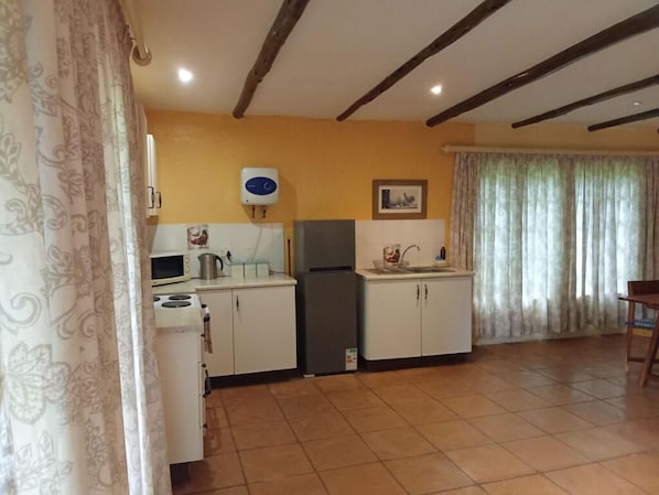 A kitchen with white cabinets, a microwave, a stove, and a refrigerator.
