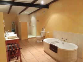Un baño con bañera, dos lavamanos, inodoro y zona de ducha.