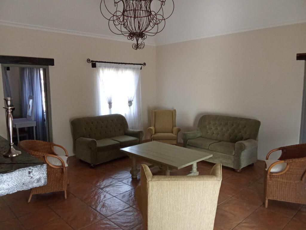 A living room with two sofas, a coffee table, and wicker chairs.