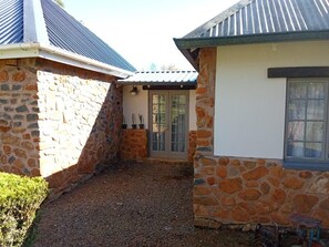 A stone building with a door and windows, a gravel path, and a small garden area.