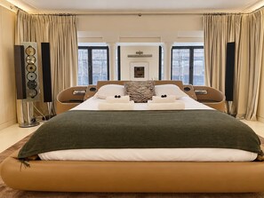 Une chambre d’hôtel avec un grand lit, deux tables de chevet, un téléviseur à écran plat et une grande fenêtre avec des rideaux.
