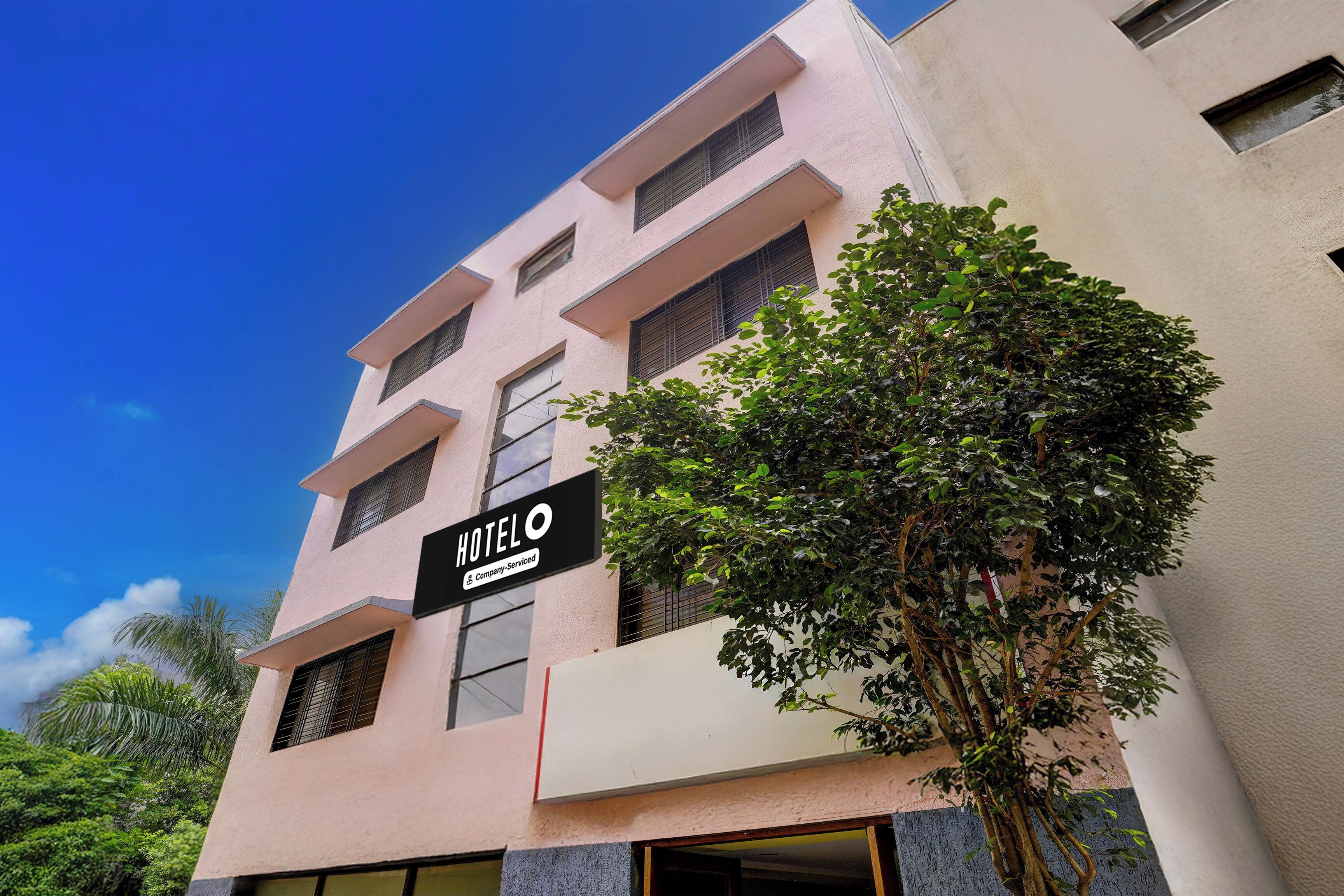 A multi-story hotel building with a sign indicating it is company-serviced.