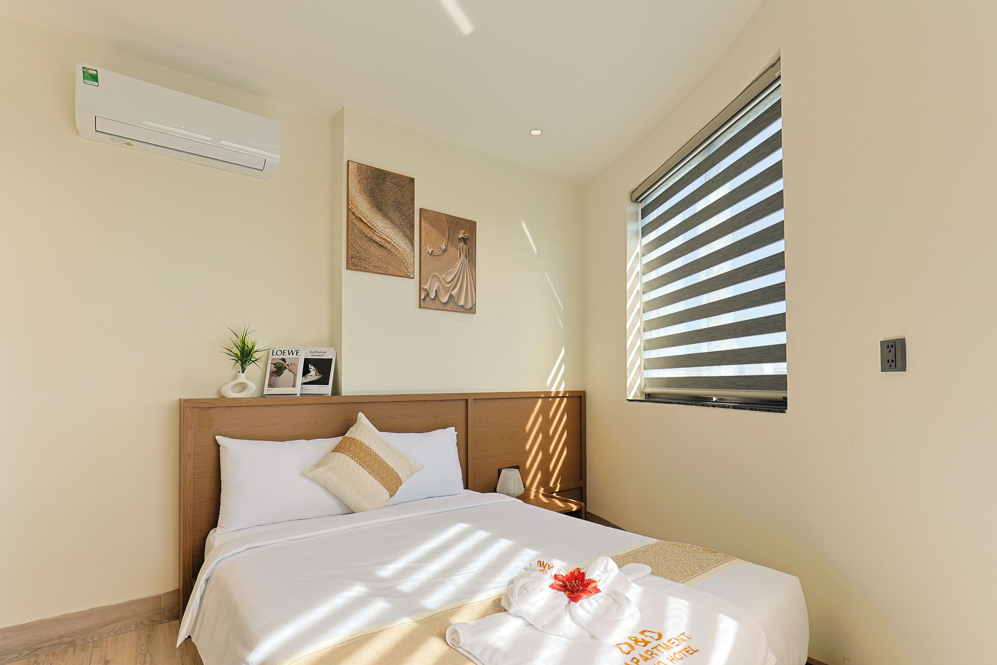 Una habitación de hotel con una cama, una mesita de noche, aire acondicionado de pared y una ventana con persianas.