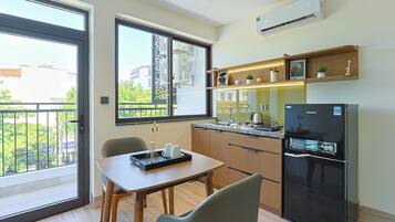 Et moderne køkken med et køleskab, et spisebord og et vindue med udsigt til en balkon.