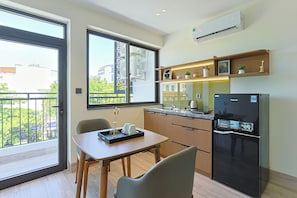 A modern kitchen with a refrigerator, a dining table, and a window overlooking a balcony. - D&D Apartment & Hotel (Ngo thi sy)