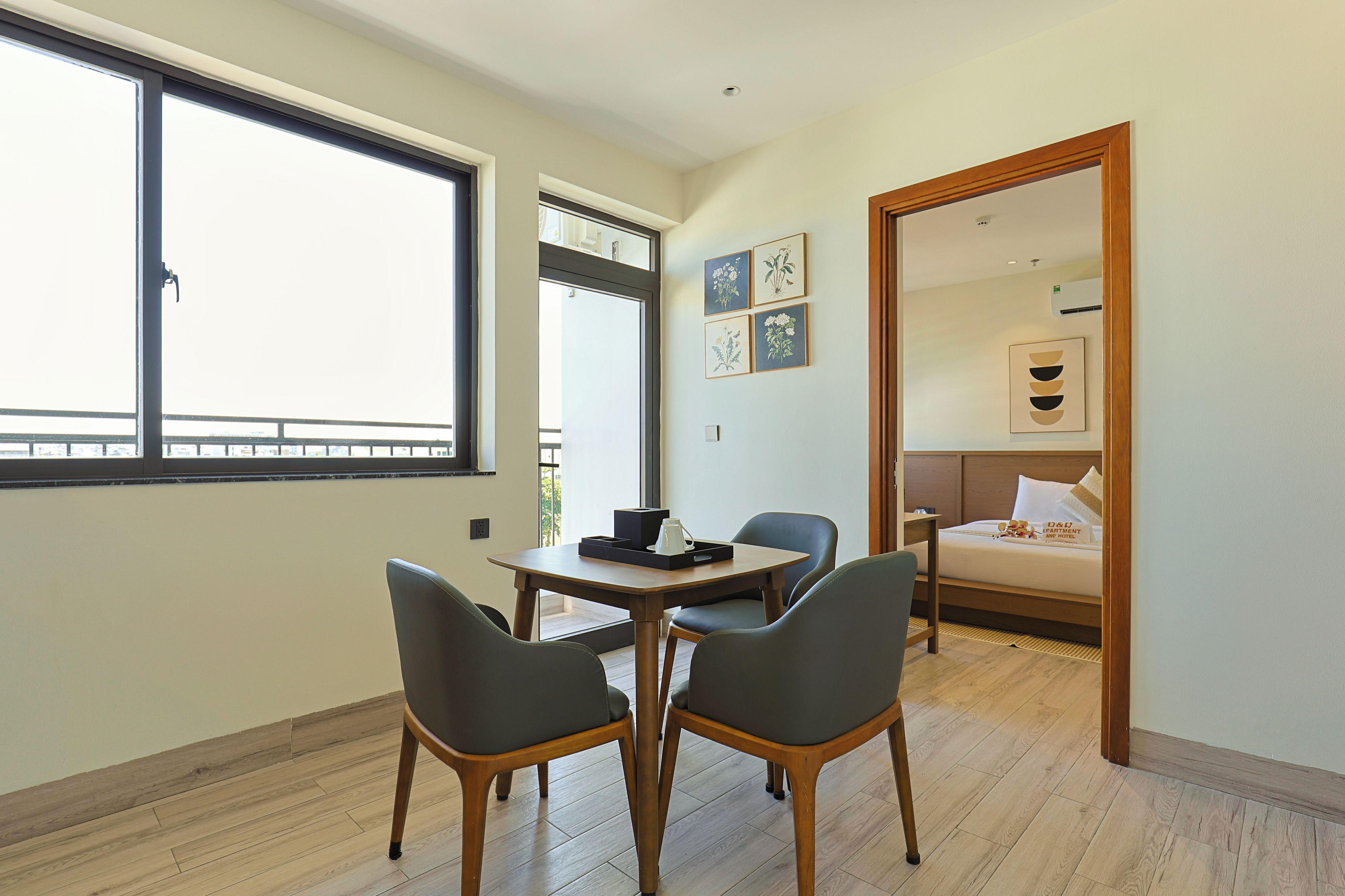 Une chambre d’hôtel avec un lit, une table et des chaises, une fenêtre et une porte donnant sur une autre pièce.