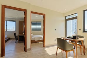 A hotel room with a bed, a desk, and a chair. There is a view of the city through the window. - D&D Apartment & Hotel (Ngo thi sy)
