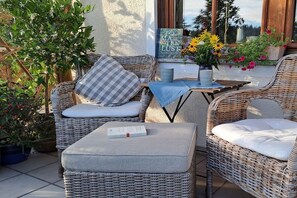 A wicker outdoor seating area with cushions, a book, and a vase of flowers. - Holiday apartment in Badenweiler with balcony (Badenweiler)
