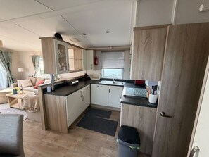 A compact kitchen with a sink, toaster, and cabinets, adjacent to a living area with a sofa and a coffee table. - Klein Vink Vacation Park - Boulevard 36 (Arcen)