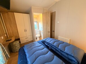 A bedroom with a bed, wardrobe, and a bathroom visible through an open door. - Klein Vink Vacation Park - Boulevard 36 (Arcen)