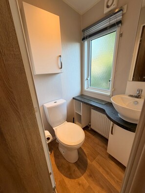 A compact bathroom with a toilet, a sink, and a window. - Klein Vink Vacation Park - Boulevard 36 (Arcen)