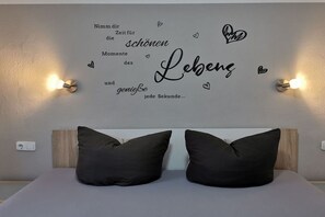 A bedroom with a bed, two pillows, a wall with a heart-shaped decoration, and two wall-mounted lights. - Michaela for nature lovers (Bad Kohlgrub)