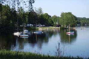 A calm lake with several boats anchored, surrounded by trees and a grassy area. - Michaela for nature lovers (Bad Kohlgrub)