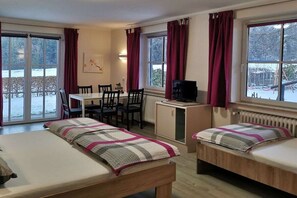A room with two beds, a desk, a chair, a television, and large windows with curtains. - Michaela for nature lovers (Bad Kohlgrub)