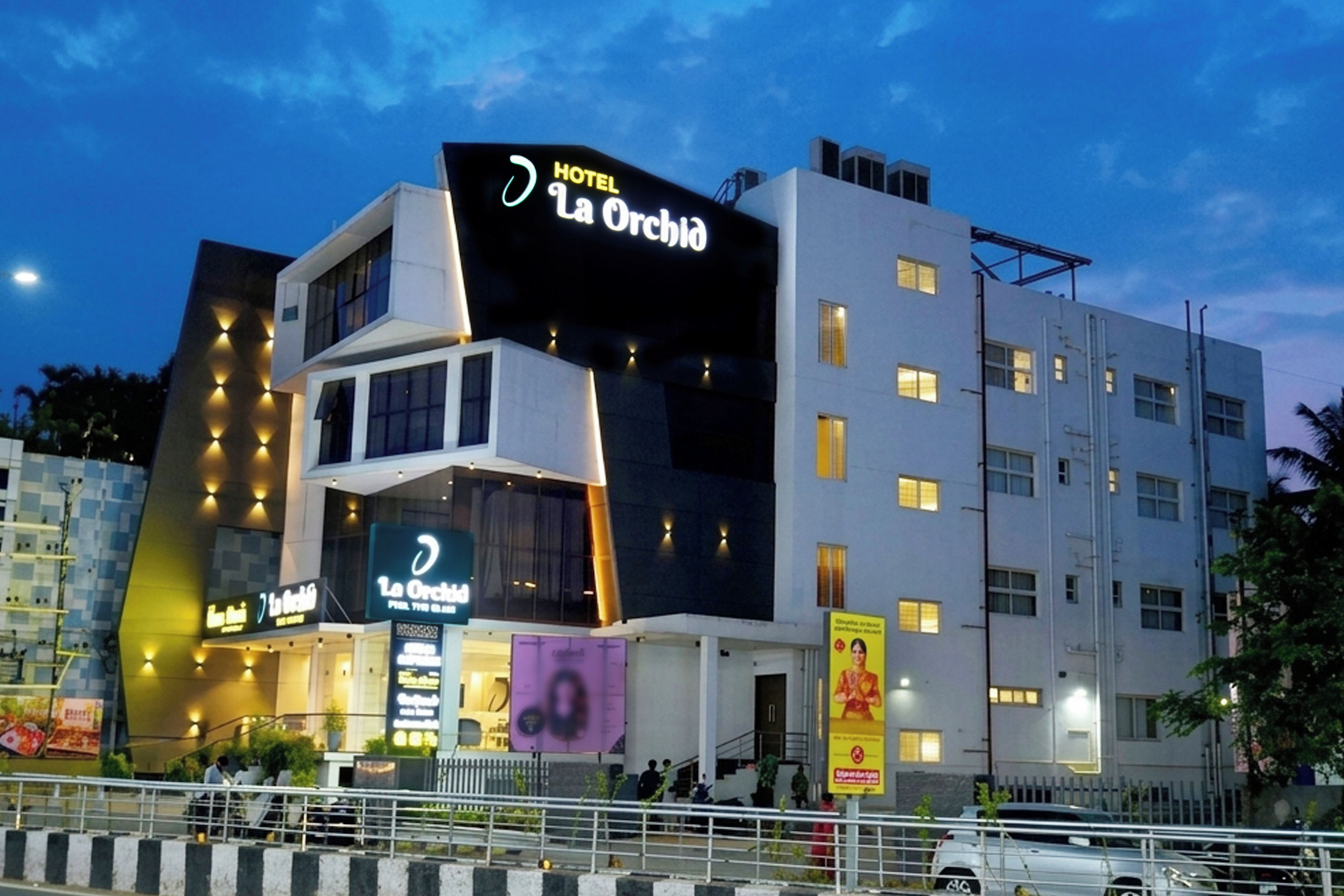 Un hotel de diverses plantes amb un cartell ben visible que diu 'HOTEL La Orchid'.