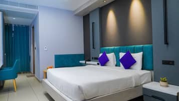 Una moderna camera d'albergo con un letto grande, una testiera blu e un comodino con una pianta.