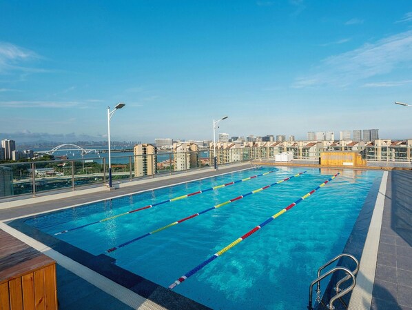 A rooftop swimming pool with clear blue water, surrounded by a cityscape view. - Lavande Hotel (Xiamen)